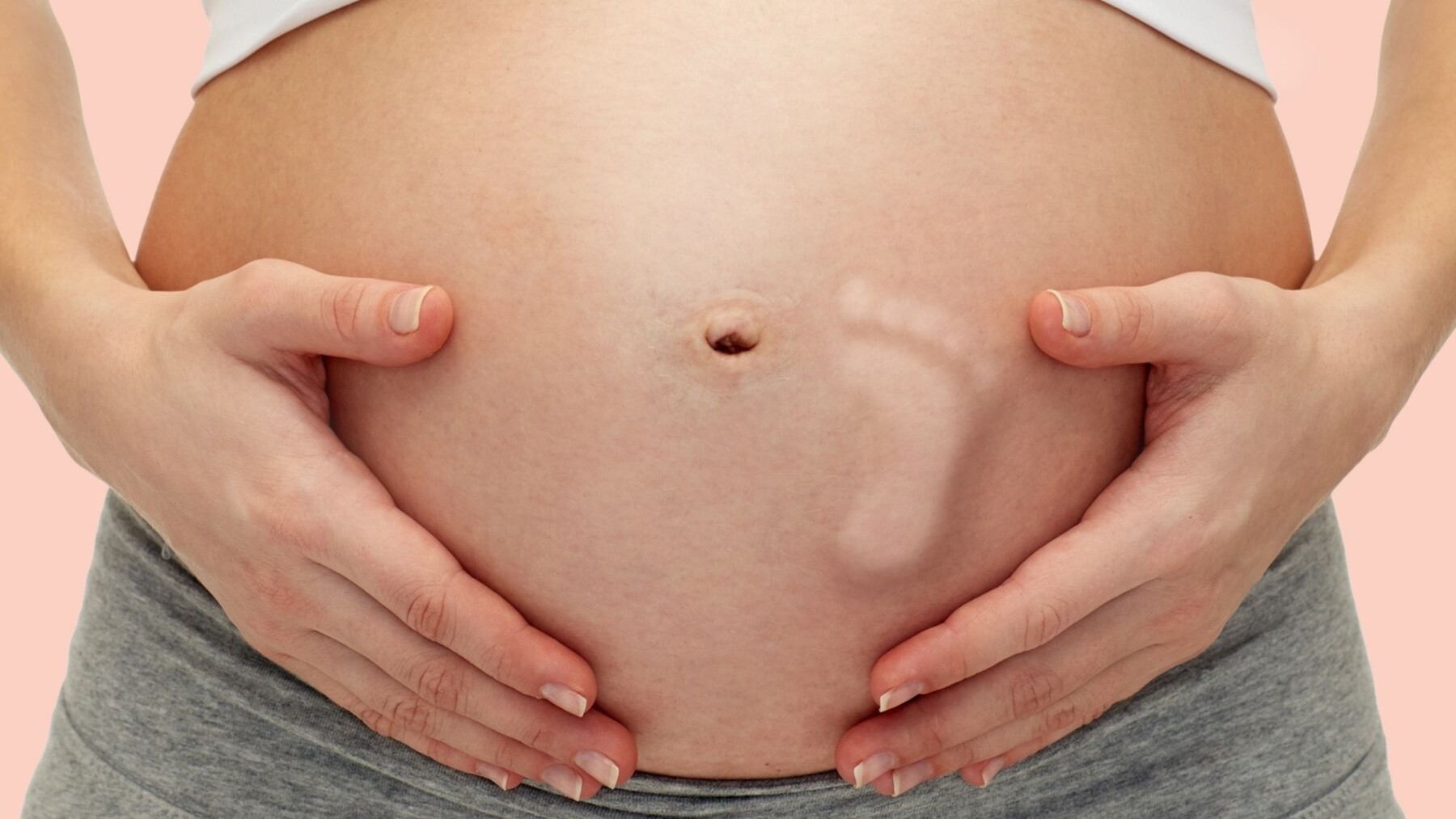 zoom sur le ventre d'une femme enceinte, le pied du bé est visible sur le ventre